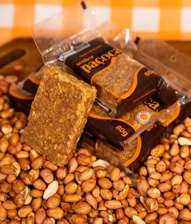 Paçocas artesanais Senhor Paçoca de 80 g, na embalagem marrom, sobre amendoins